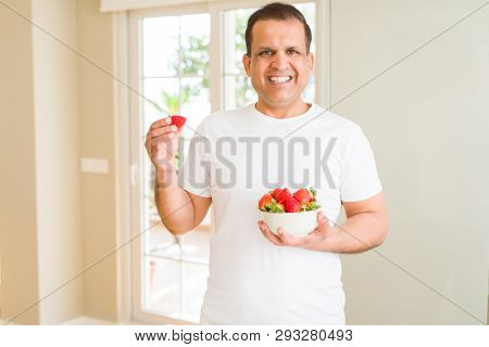 Middle age man eating straweberry at home