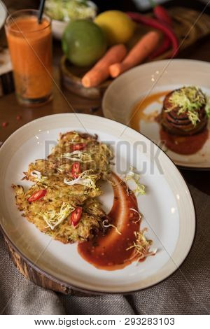 Healthy vegeterian food on brown wood board. Potato vegan pancakes with juice fruit and vegetables