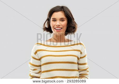 people concept - happy smiling young woman in striped pullover over grey background