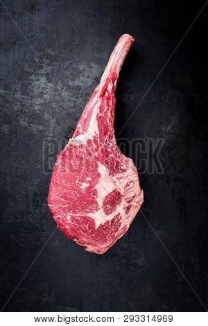 Traditional raw dry aged angus tomahawk steak as top view on an old rustic board