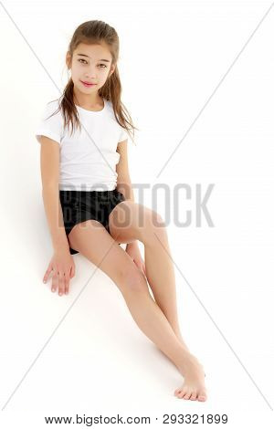 A Cute Little Girl Leaned Against A White Wall. Cyclorama In Studio. Isolated On A White Background.