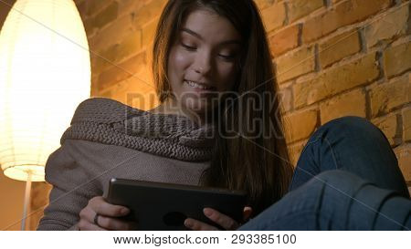 Closeup Portrait Of Young Attractive Caucasian Female Using The Tablet While Resting Laidback On The