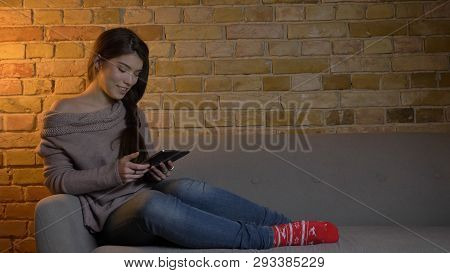 Closeup Portrait Of Young Attractive Caucasian Female Using The Tablet While Resting Laidback On The