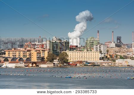 Wite Smoke Going Up From The Chimney. Taranto Steel Industry Crossing The Old City, Puglia. Italy