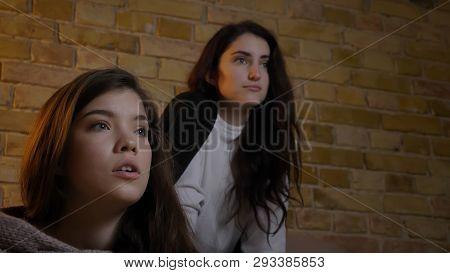 Closeup Portrait Of Two Young Cute Girls Watching Tv Together Witn Excited Facial Expressions
