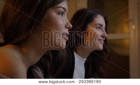 Closeup Portrait Of Two Young Pretty Women Watching Tv Laughing Happily In A Cozy Apartment Indoors