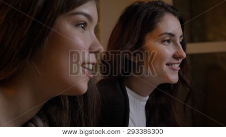 Closeup Side View Portrait Of Two Young Pretty Women Watching Tv Being Cheerful In A Cozy Apartment 