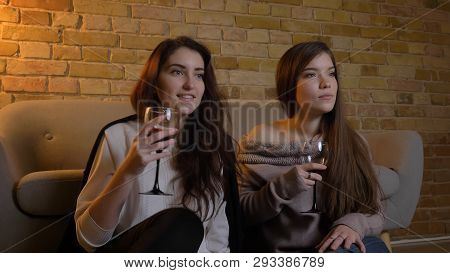 Closeup Portrait Of Two Young Pretty Women Watching A Movie Tv Chilling With Wine Sitting On The Flo