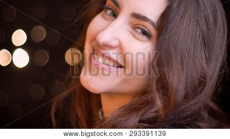Closeup Side View Shoot Of Young Seductive Caucasian Female Smiling With Charm While Looking Straigh