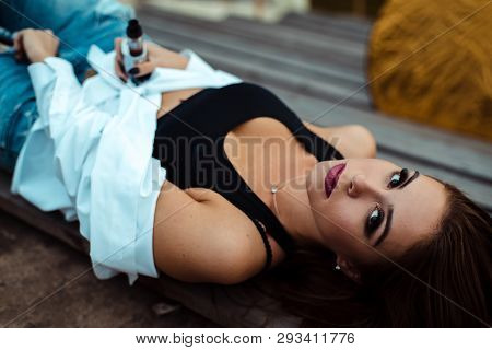 Young Sexy Woman Lies On A Wooden Bench. She Is Taking Break After Workout In Gym. Outdoor