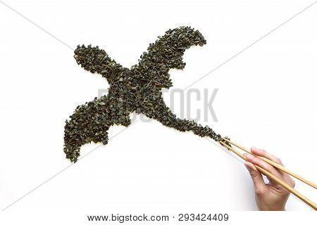 Chopsticks In Hand Holding Dragon By Tail Made From Dry Green Tea On White Background. Minimal, Crea
