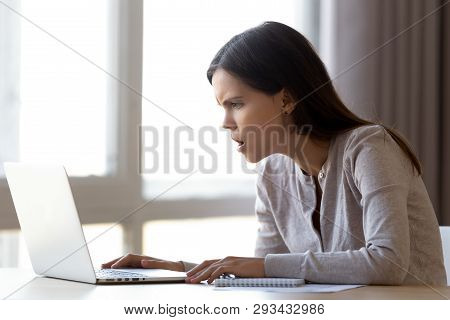 Annoyed Female Sitting At Desk Looking On Laptop Screen