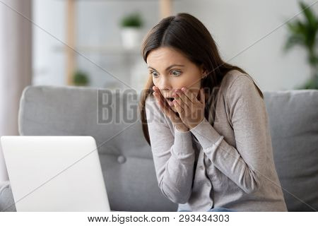 Woman Sitting On Couch Reading Message On Computer Feels Shocked