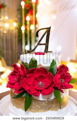 Two Storey White Cake With Flowers, The Letter A, And A Golden Edging On The Background Of Flowers A