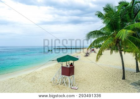 Tropical Caribbean Island Beach Scene. Life Guard Tower, Coconut Palm Trees, White Sand.