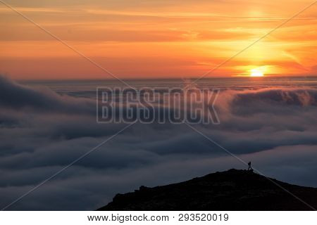 Silhouette Of A Man On The Ridge Above The Sea Of Clouds, Misty Mountains At Sunset In Iceland