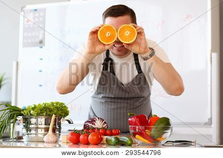Man Holds Halves Of Cut Orange As Eye Glasses Portrait Background Concept