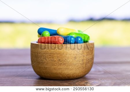 Lot Of Whole Sweet Licorice Comfit Closeup In A Wooden Bowl With Green Wheat Field In Background