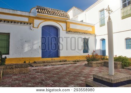 Spanish Brightly Colored Courtyard Or Patio In The Sun With An Ornate Cross On A Column