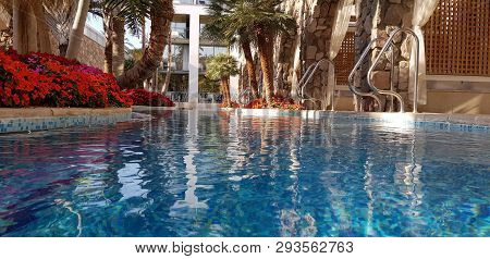 Blue Swimming Pool View From Water Level Near Luxury Hotel Rooms With Pool Entrance From The Balcony