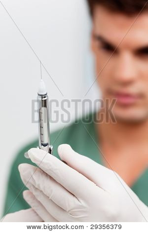 Close-up do jovem médico usando luvas de borracha e segurando a injeção