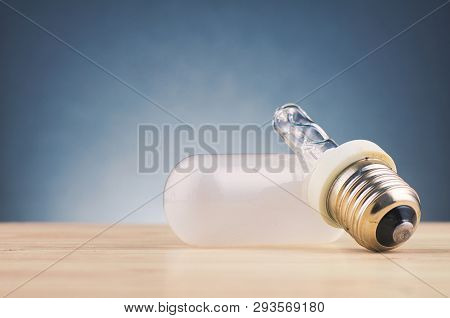 Problem In Thinking And Thoughtless Concept, Broken Light Bulb On Wooden Desk Over Gently Lit Dark B