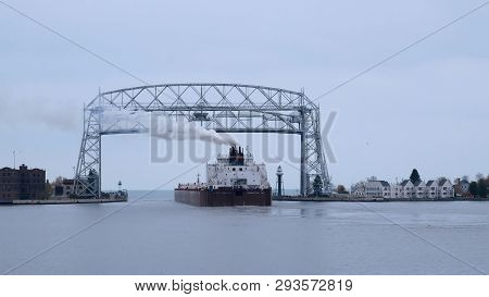 Duluth, Mn - 27 Oct 2018: The Iconic Aerial Lift Bridge With An Iron Ore Ship Departing For Lake Sup