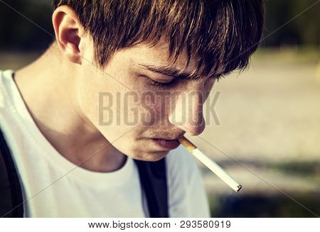Toned Photo Of Sad Young Man Smoking A Cigarette Outdoor Closeup