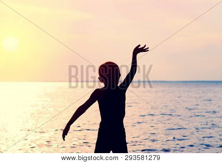 Toned Photo Of Child Silhouette Waving His Arm On The Sea Background