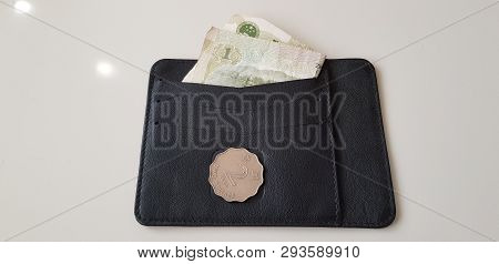 Two Hong Kong Dollars Coin Lay On Black Leather Wallet With One Yuan Banknote Folded In It