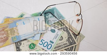 Banknotes Of Hryvnia Dynars And Dollars Near Eyeglasses On White Table