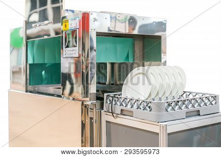 Close Up White Plate On Basket In Automatic Dishwasher Machine For Industrial Isolated On White Back