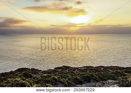 Cliff Side View Of Pacific Ocean At Sunrise With Sunrays
