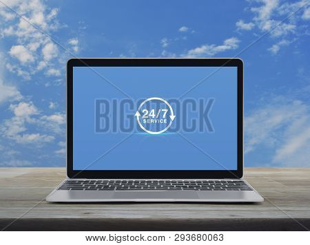 247 Service Icon With Modern Laptop Computer On Wooden Table Over Blue Sky With White Clouds, Busine