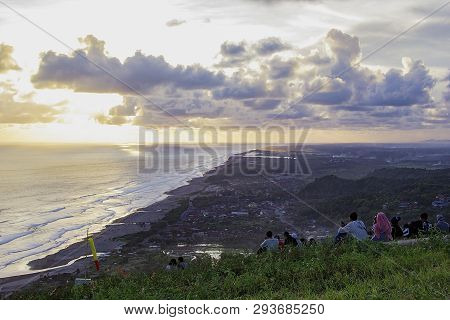 People Sitting On The Ground And Watch For Sun Set Paragliding Hill Watugupit At Yogyakarta