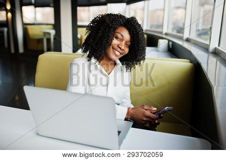 Сheerful Business African American Lady With Afro Hair, Wear White Blouse Sitting At Table And Work