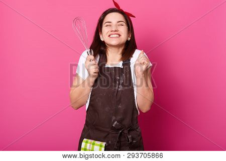 Smiling Cheerful Girl Clenches Fists With Kitchen Equipment In Right Hand, Wears Work Clothing, Bein