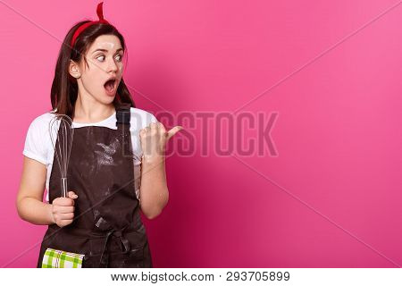 Surprised Dark Haired Woman Makes Gesture With Her Thumb. Gifted Active Baker Holds Kitchen Equipmen