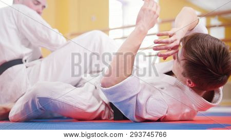 Two Athletic Men Training Their Aikido Skills In The Studio. Throwing The Opponent On The Floor