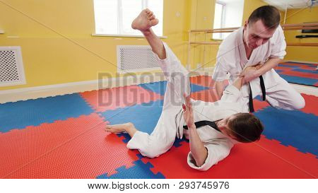 Two Athletic Men Training Their Aikido Skills In The Studio. A Man Grabs His Opponent And Throws Him