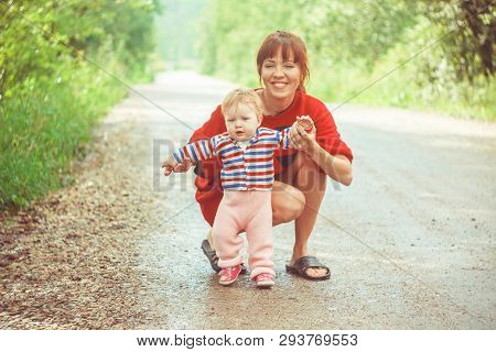 The Child Learns To Walk In The Park Barefoot On The Grass