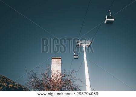 View From Below: Two Modern Ropeway Cabins And The Basic Pole Of The Contemporary Cableway On A Sunn