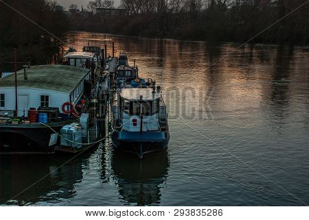 Many House Boats Are Beached On The Side Of The River Thames At Sunset