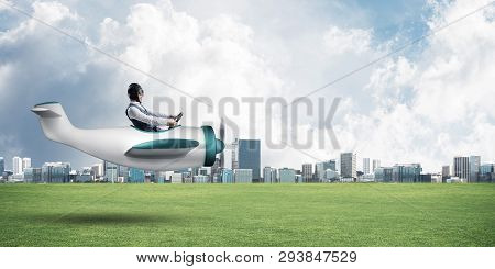 Young Aviator Driving Small Propeller Plane. Modern Metropolis With High Buildings On Background. Ma