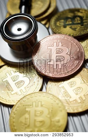Bitcoins and stethoscope on a metal table.
