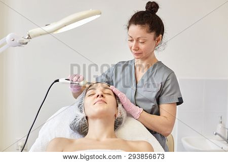 Ultrasonic Cleaning Of Face. Young Girl Has Ultrasound Peeling. Cosmetologist Makes Procedure For Sk