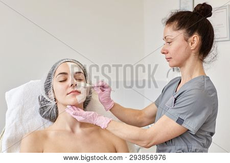 Cosmetologist Makes Procedure Of Cleansing And Moisturizing Of Skin, Applying Mask With Special Brus