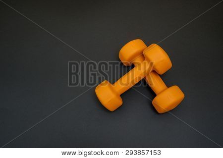 Two Orange Dumbbells Isolated On Black Background