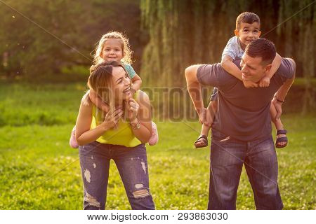 Happy Family -happy Family Piggyback Their Children And Have Fun Together In Park