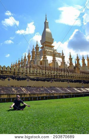 Vientiane Laos - 02.03.2019: Young Man In Black Sitting On The Grass And Meditating Near The Golden 